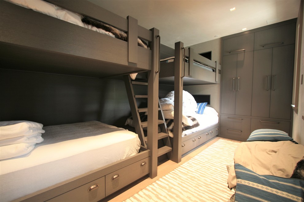 Modelo de habitación de invitados minimalista de tamaño medio sin chimenea con paredes grises y suelo de madera clara