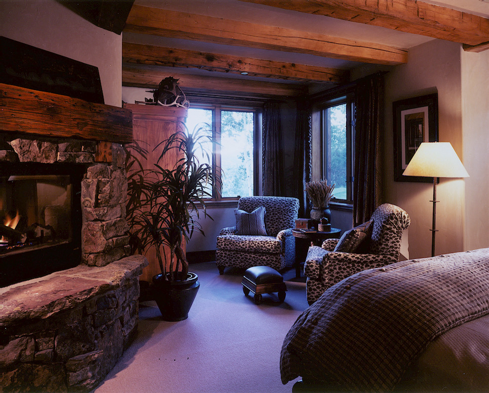 Foto de habitación de invitados rural grande con paredes beige, moqueta, todas las chimeneas y marco de chimenea de piedra