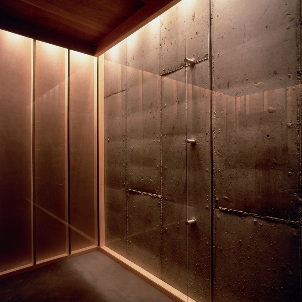 Foto di una camera degli ospiti minimalista di medie dimensioni con pareti grigie, pavimento in cemento, nessun camino e cornice del camino in pietra