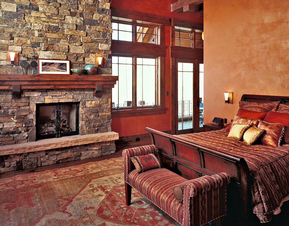 На фото: огромная хозяйская спальня в классическом стиле с оранжевыми стенами, паркетным полом среднего тона, стандартным камином и фасадом камина из камня