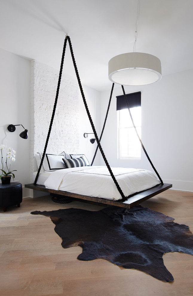 Immagine di una camera da letto design di medie dimensioni con pareti bianche, parquet chiaro e nessun camino