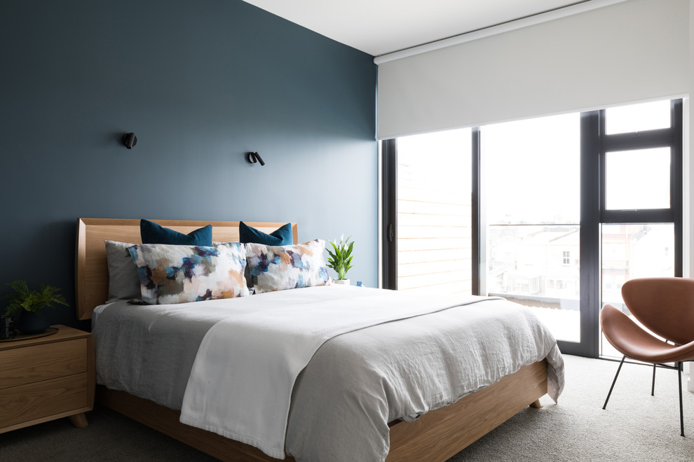 Modernes Schlafzimmer mit blauer Wandfarbe, Teppichboden und grauem Boden in Auckland