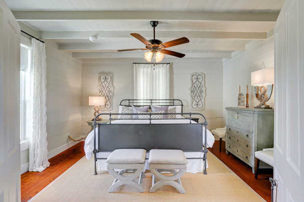 Idée de décoration pour une chambre parentale tradition avec un mur blanc, un sol en bois brun et un sol marron.