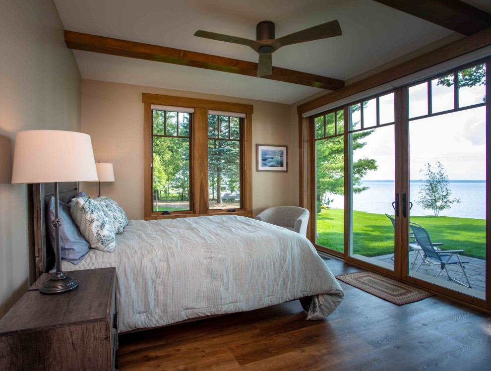 Großes Hauptschlafzimmer mit beiger Wandfarbe, braunem Holzboden, braunem Boden und freigelegten Dachbalken in Sonstige