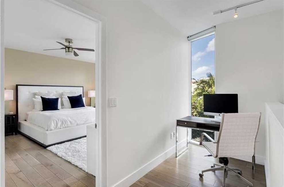 Large contemporary master bedroom in Miami with white walls, medium hardwood flooring and no fireplace.