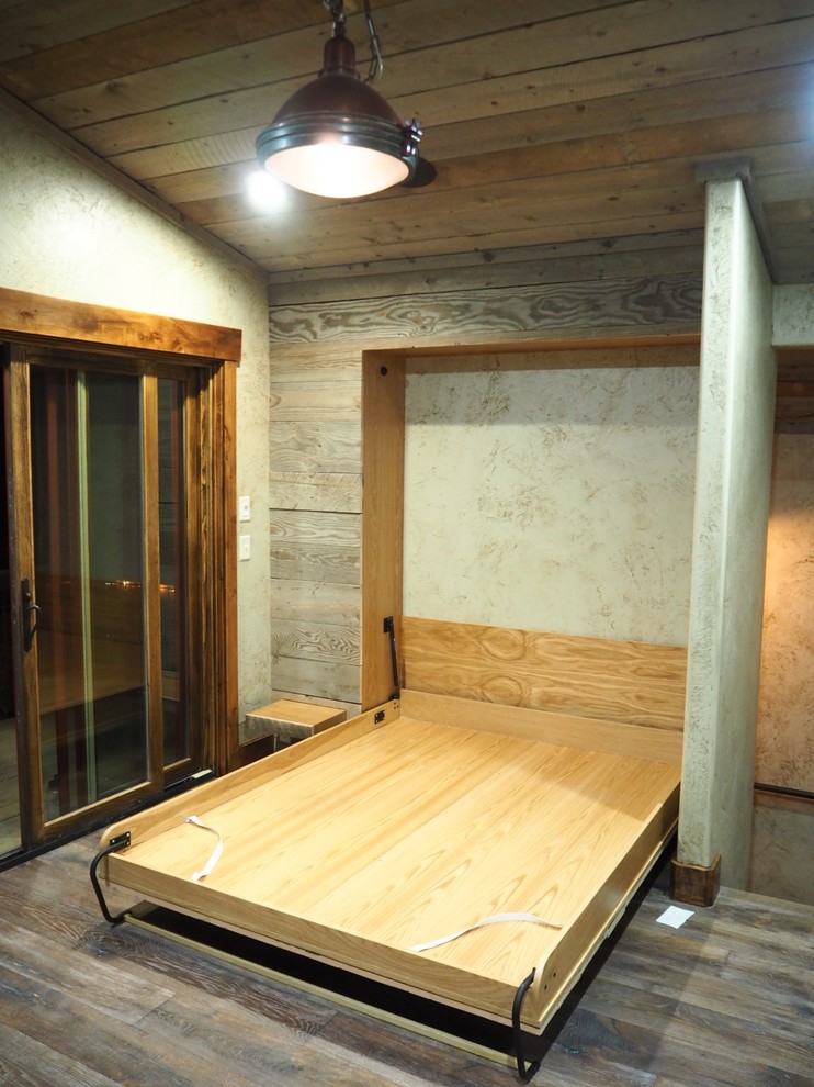 Modelo de habitación de invitados rústica de tamaño medio sin chimenea con paredes grises, suelo de madera en tonos medios y suelo marrón