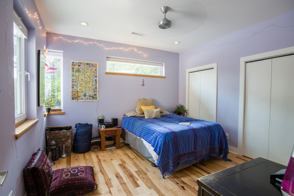 Modelo de habitación de invitados contemporánea de tamaño medio con paredes púrpuras y suelo de madera en tonos medios