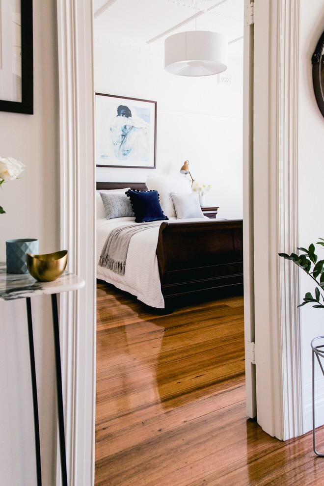 Großes Skandinavisches Hauptschlafzimmer mit weißer Wandfarbe und braunem Holzboden in Melbourne