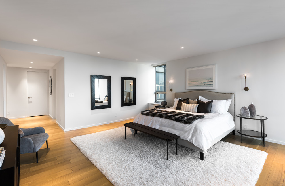Design ideas for a large contemporary master and grey and cream bedroom in New York with white walls and light hardwood flooring.