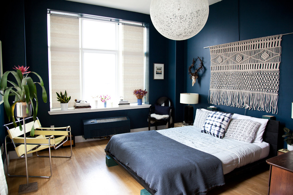 Modelo de dormitorio principal moderno grande con paredes azules y suelo de madera clara