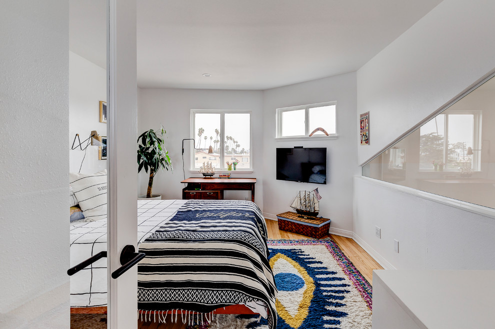 Example of a beach style master light wood floor and beige floor bedroom design in Los Angeles with white walls
