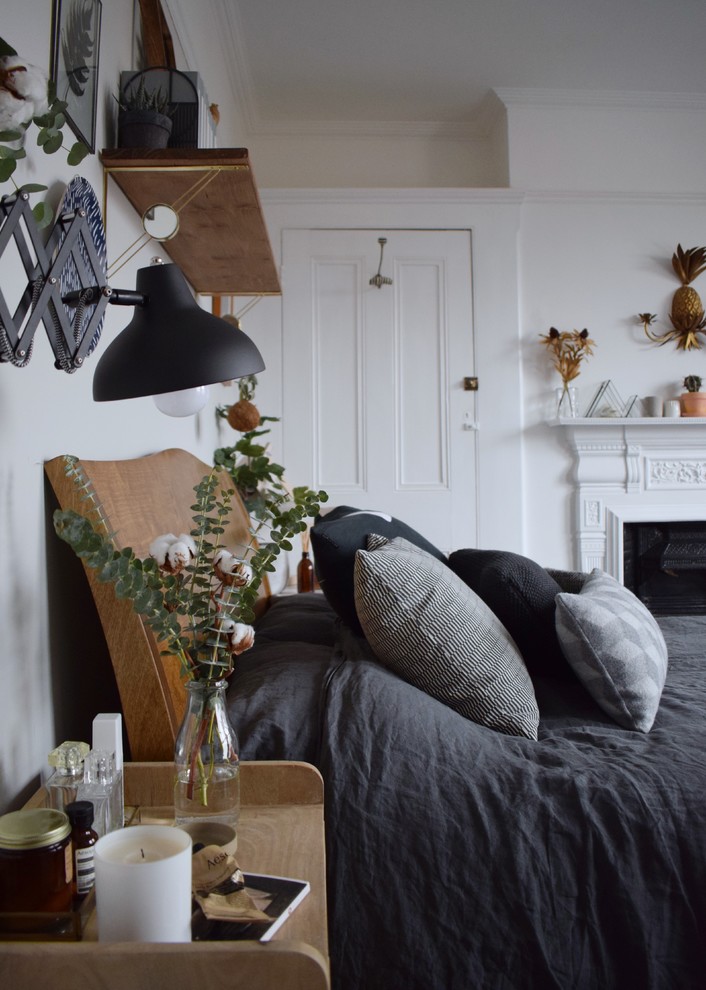 ロンドンにある広い北欧スタイルのおしゃれな主寝室 (白い壁、塗装フローリング、両方向型暖炉、金属の暖炉まわり、黒い床)