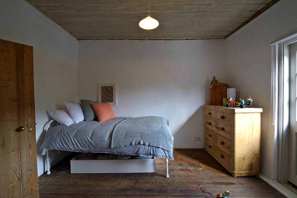 Inredning av ett shabby chic-inspirerat sovrum, med vita väggar och mörkt trägolv