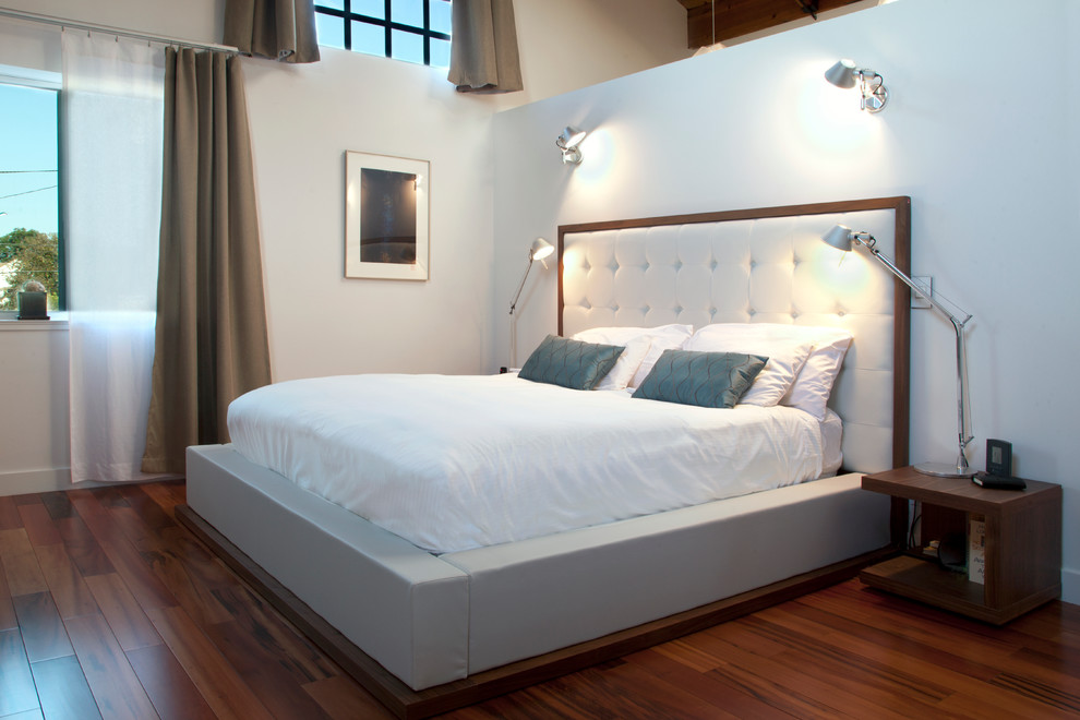 Imagen de dormitorio contemporáneo con paredes blancas y suelo de madera en tonos medios