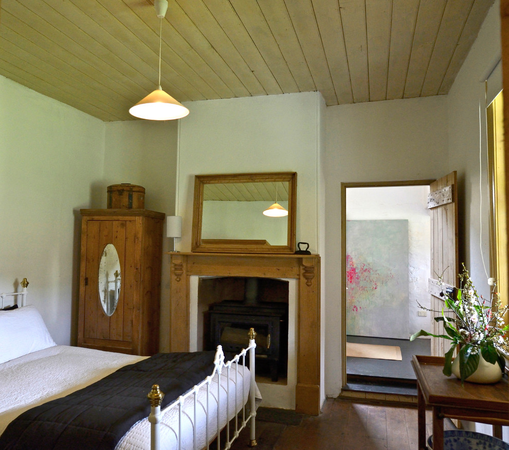 Foto på ett lantligt sovrum, med vita väggar och en standard öppen spis