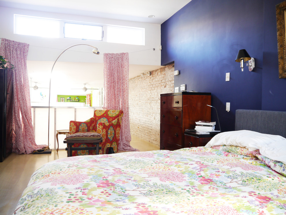Exemple d'une chambre parentale éclectique de taille moyenne avec un mur bleu et parquet clair.