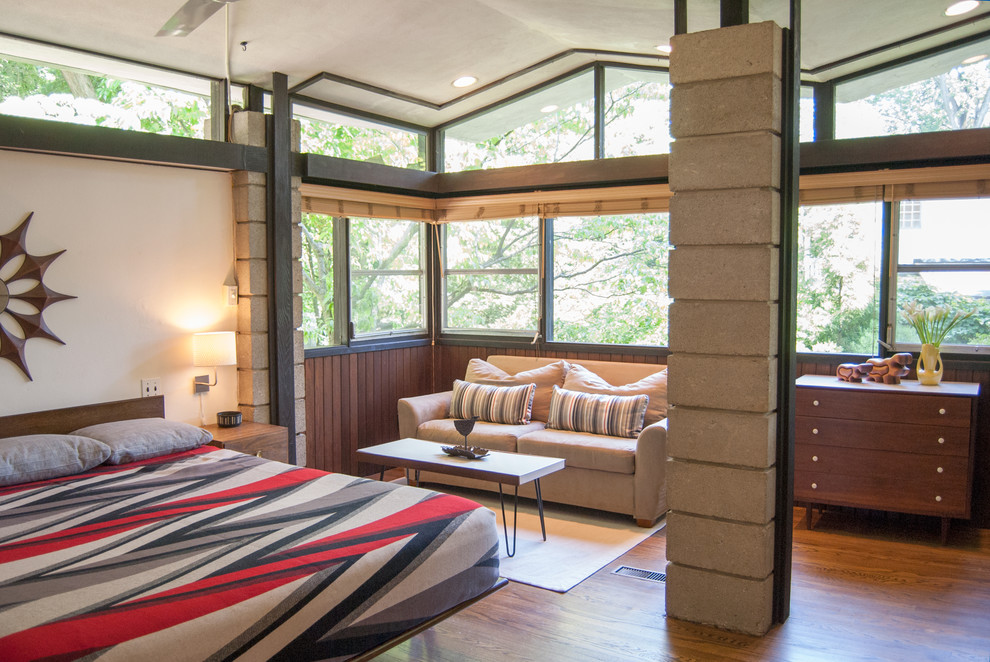 Immagine di una camera da letto minimalista con pareti bianche e pavimento in legno massello medio