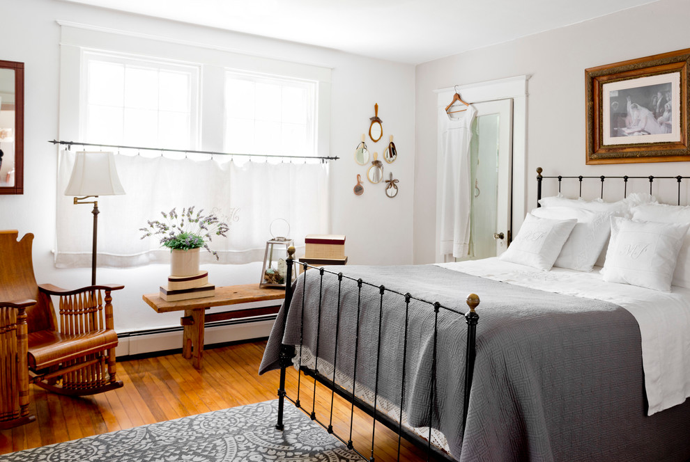 Photo of a classic bedroom in New York with grey walls, medium hardwood flooring and orange floors.