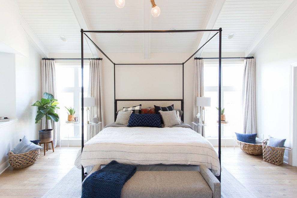 Ejemplo de dormitorio principal costero grande sin chimenea con paredes beige y suelo de madera clara