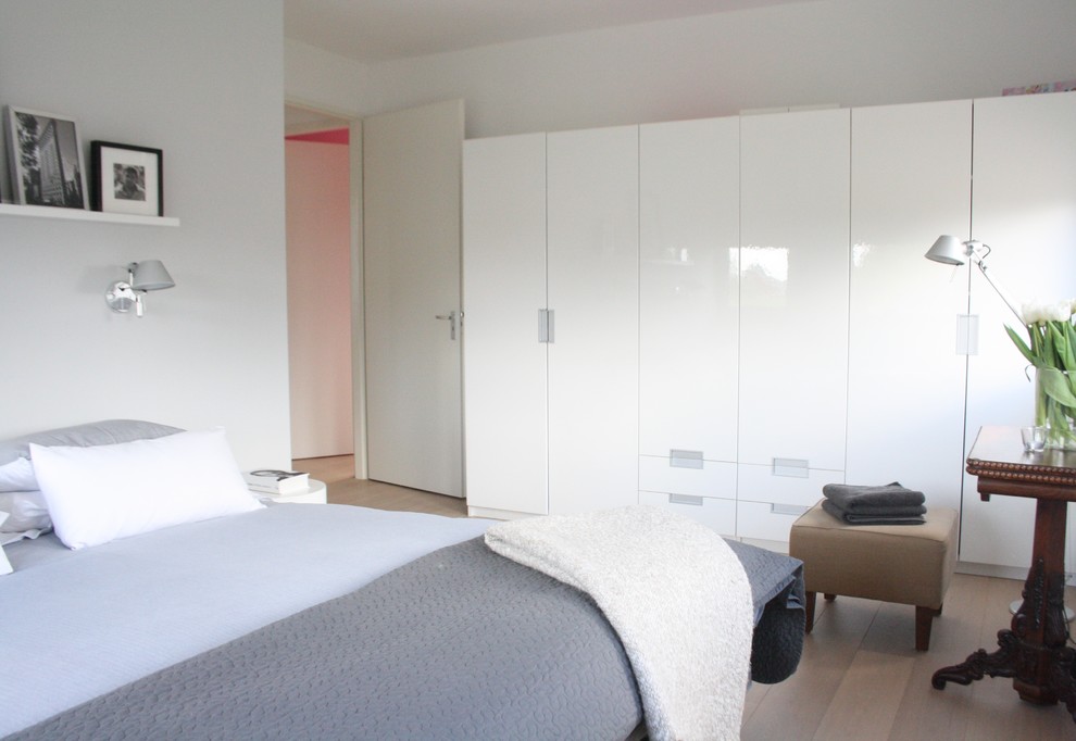 Esempio di una camera da letto contemporanea con pareti bianche e parquet chiaro