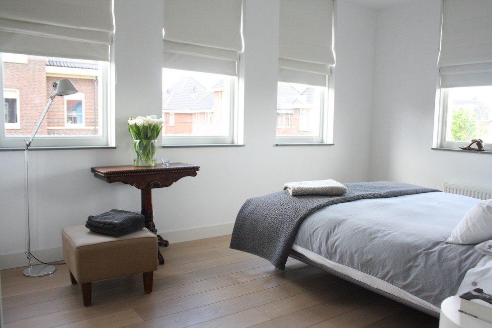Modernes Schlafzimmer mit weißer Wandfarbe und braunem Holzboden in Amsterdam