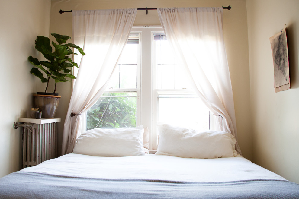 Modelo de dormitorio principal bohemio pequeño con paredes blancas y suelo de madera en tonos medios