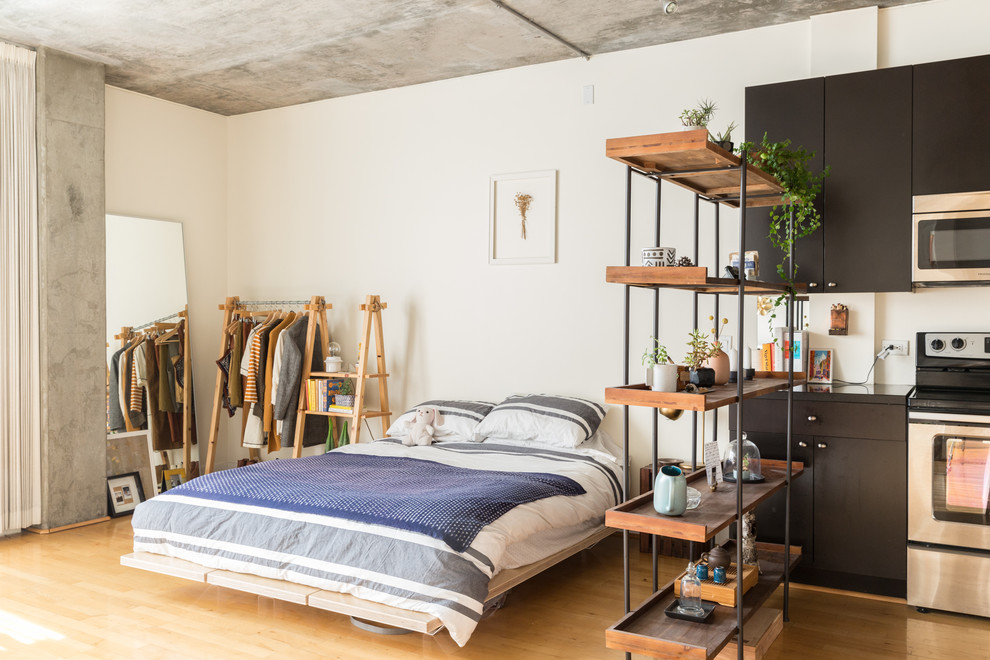 Modelo de dormitorio industrial con paredes blancas, suelo de madera en tonos medios y suelo marrón
