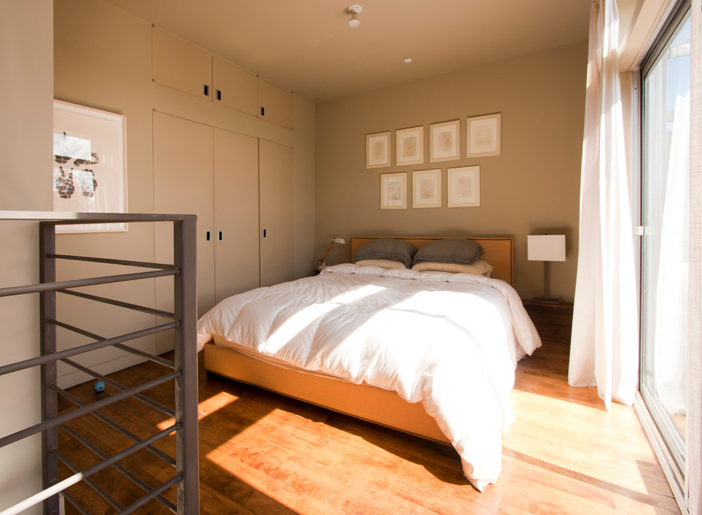 Bedroom - industrial medium tone wood floor bedroom idea in New York with beige walls