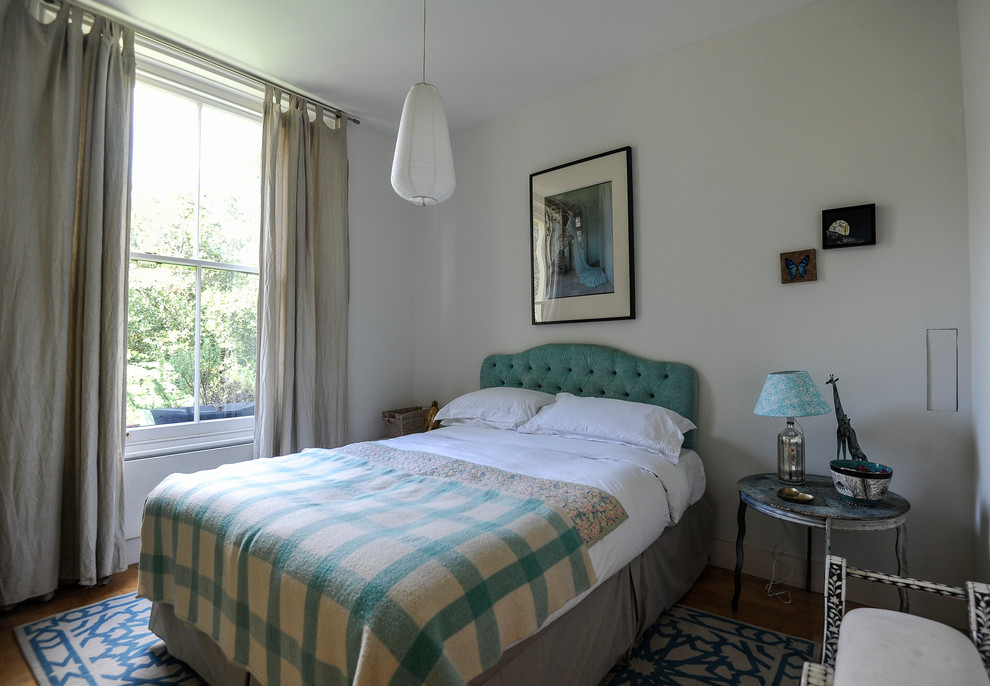 Exemple d'une chambre d'amis éclectique avec un mur blanc, aucune cheminée et un sol en bois brun.