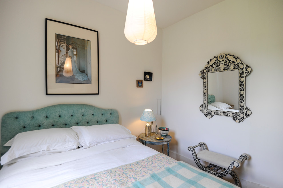 Foto de habitación de invitados ecléctica pequeña sin chimenea con paredes blancas y suelo de madera en tonos medios