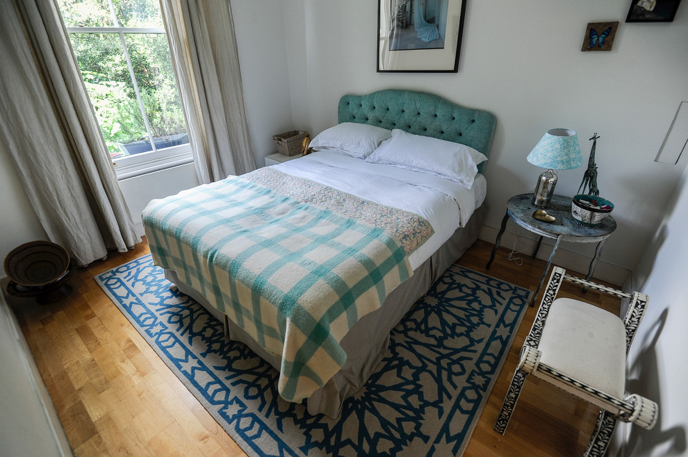Foto de habitación de invitados bohemia pequeña sin chimenea con paredes blancas y suelo de madera en tonos medios