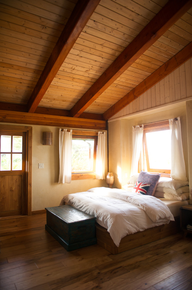 Diseño de dormitorio exótico con paredes beige y suelo de madera oscura