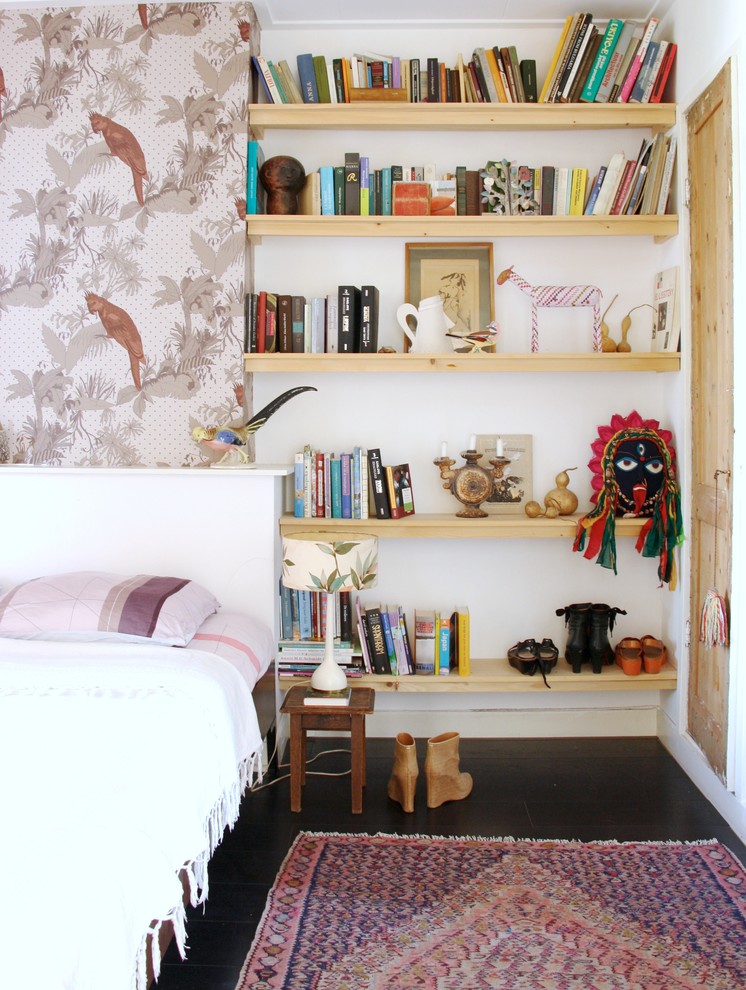 Foto på ett minimalistiskt sovrum, med vita väggar och mörkt trägolv