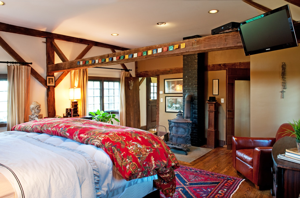 Ejemplo de dormitorio televisión de estilo de casa de campo con paredes beige, suelo de madera oscura y estufa de leña