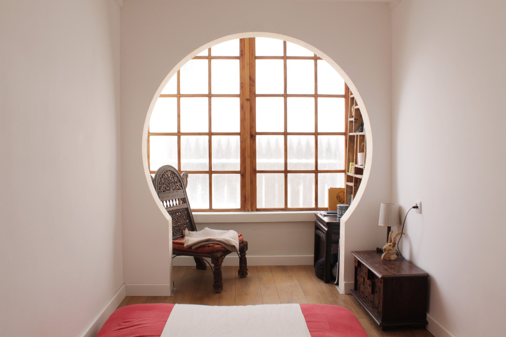 Foto på ett eklektiskt sovrum, med vita väggar och mellanmörkt trägolv