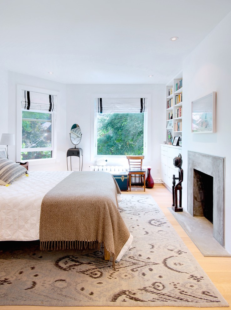 Ejemplo de dormitorio principal nórdico de tamaño medio con paredes blancas, suelo de madera clara, todas las chimeneas y marco de chimenea de hormigón