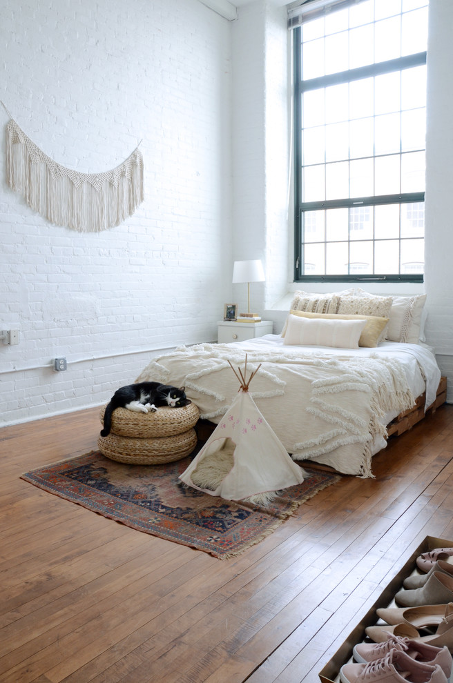 Aménagement d'une chambre éclectique avec un mur blanc, un sol en bois brun et un sol marron.