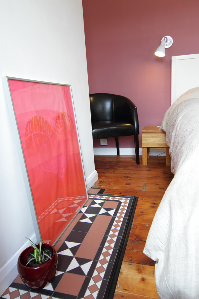 Imagen de dormitorio principal bohemio de tamaño medio con paredes rosas, suelo de madera en tonos medios y marco de chimenea de baldosas y/o azulejos