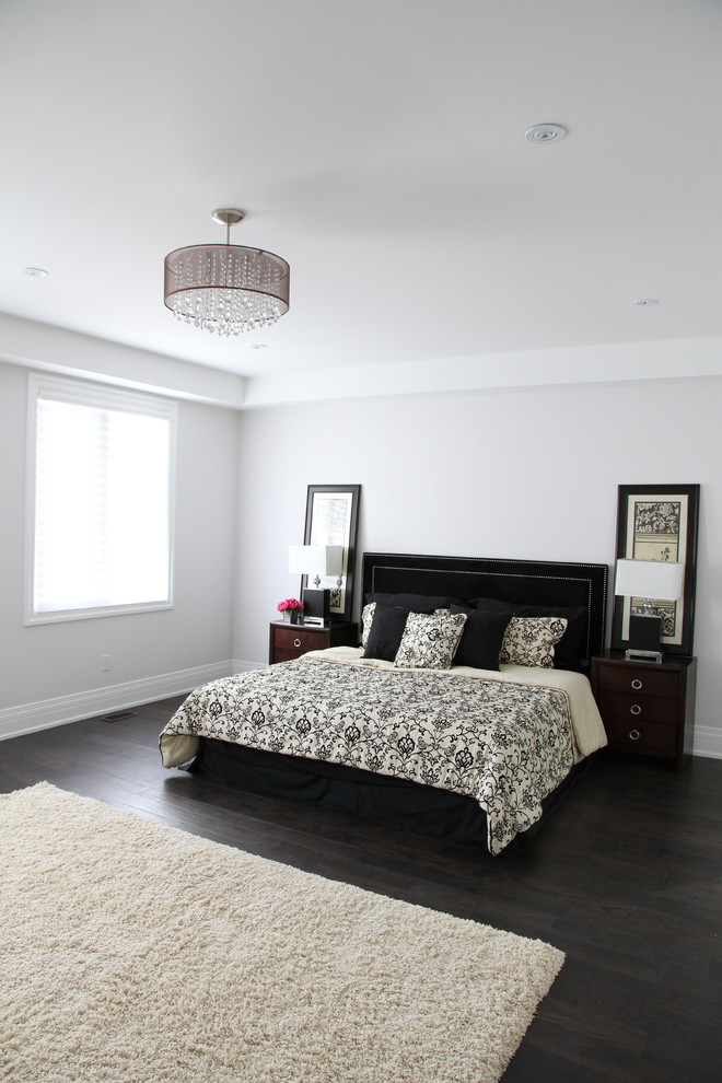 Imagen de dormitorio principal actual de tamaño medio sin chimenea con paredes grises, suelo de madera oscura y suelo marrón
