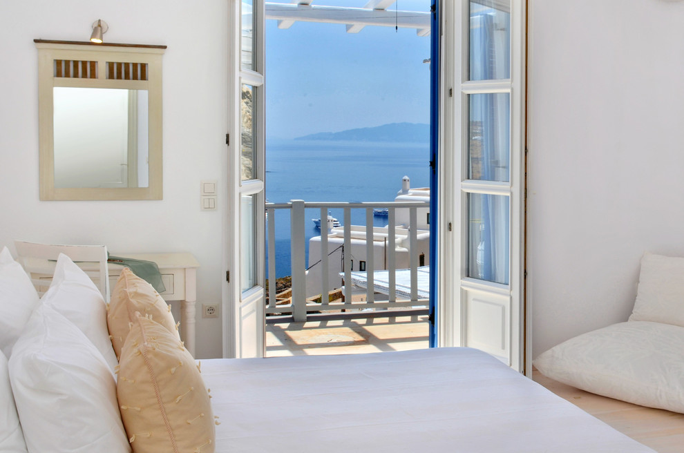 Foto de dormitorio mediterráneo con paredes blancas, suelo de madera clara y suelo beige