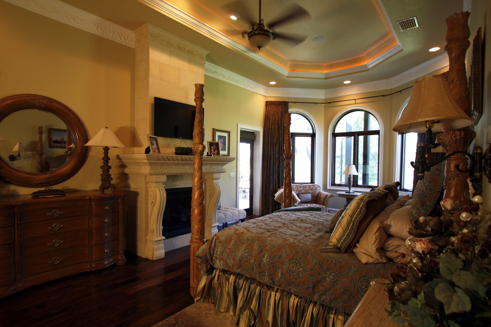 Large mediterranean master bedroom in Tampa with beige walls, dark hardwood flooring, a standard fireplace and a stone fireplace surround.