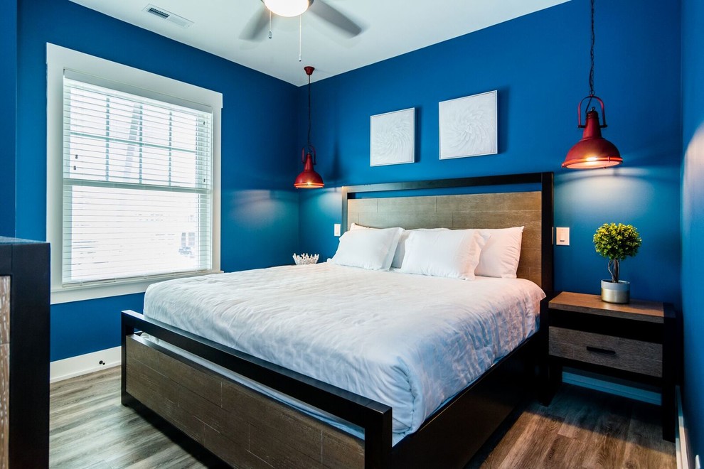 Exemple d'une petite chambre d'amis bord de mer avec un mur bleu, parquet foncé, aucune cheminée et un sol marron.