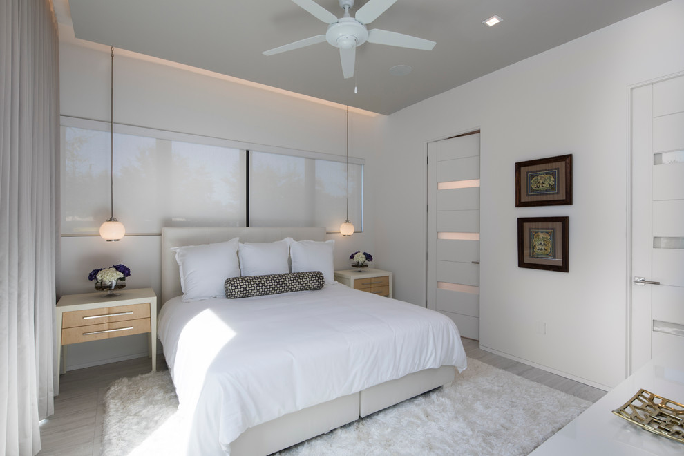 Exemple d'une grande chambre d'amis tendance avec parquet clair et un mur blanc.