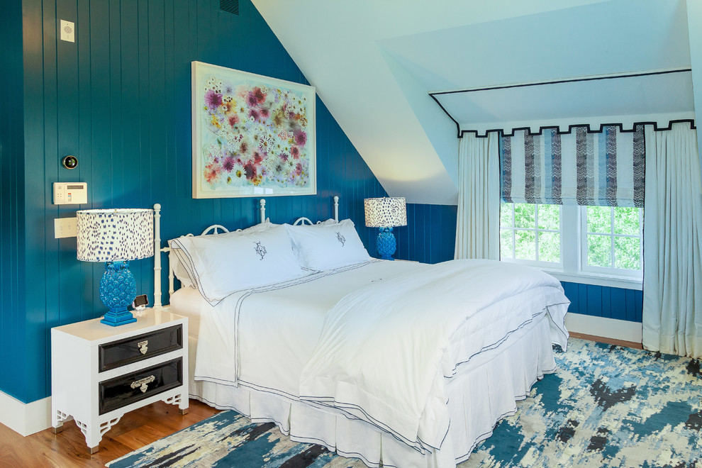 Cette image montre une chambre parentale marine de taille moyenne avec un mur bleu et un sol en bois brun.