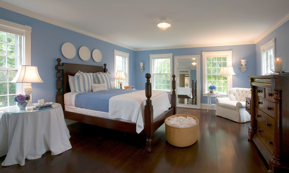 This is an example of a classic bedroom in Boston with blue walls and dark hardwood flooring.