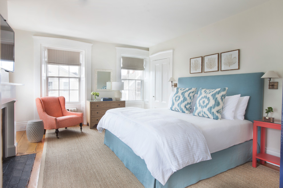 Imagen de dormitorio televisión costero con paredes blancas, suelo de madera en tonos medios y todas las chimeneas