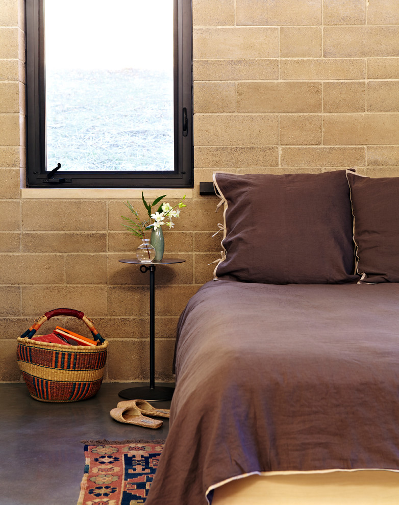 Exemple d'une chambre parentale tendance de taille moyenne avec un mur marron, sol en béton ciré et aucune cheminée.
