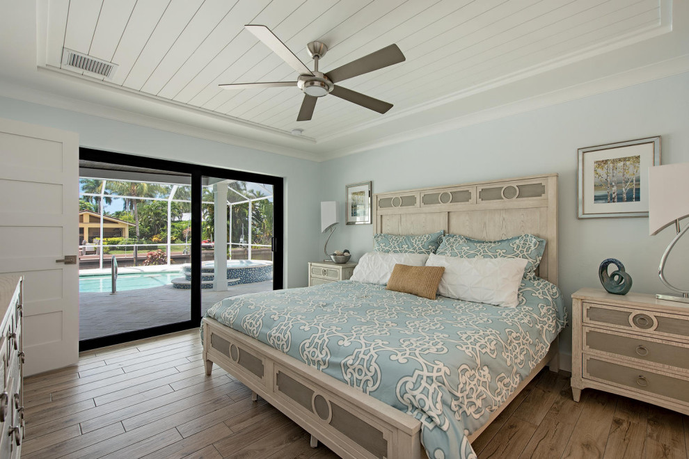 他の地域にある小さなビーチスタイルのおしゃれな主寝室 (青い壁、セラミックタイルの床、黄色い床)