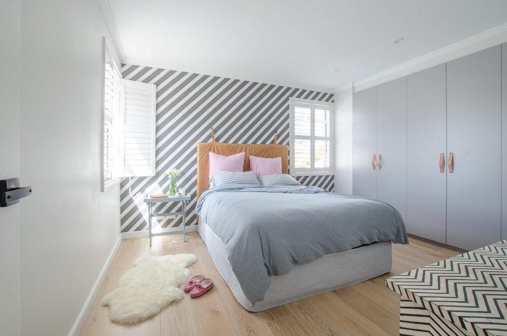 Imagen de dormitorio principal actual de tamaño medio sin chimenea con paredes blancas y suelo de madera clara