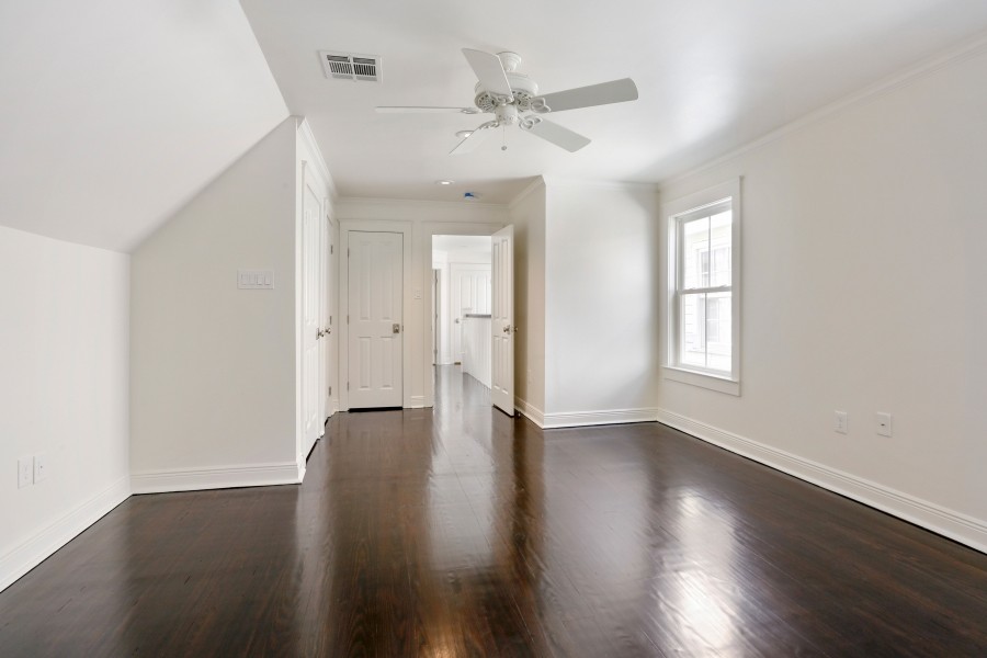 Geräumiges Klassisches Schlafzimmer im Loft-Style mit weißer Wandfarbe, dunklem Holzboden und blauem Boden in New Orleans